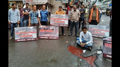 Activist Sangram Dongre sits in a pothole on Gokhale Road in Thane to protest against the bad condition of roads. (PRAFUL GANGURDE/HT PHOTO)