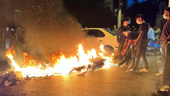 Iran Protests: A demonstrator drags a burning motorbike during a protest for Mahsa Amini, a woman who died after being arrested.(AFP)