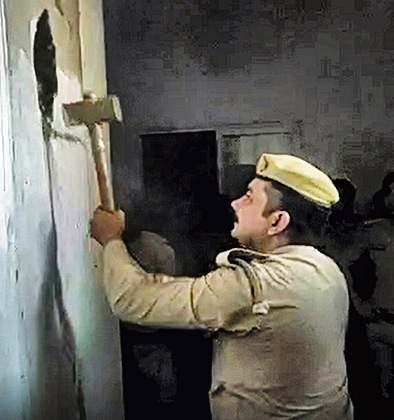 A policeman brings down a wall at Jauhar University. (PTI) A policeman brings down a wall at Jauhar University. (PTI)