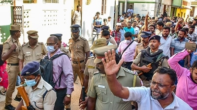 Members of Social Democratic Party of India (SDPI) raise slogans as police personnel escort officers of National Investigation Agency (NIA), in Madurai. (PTI)