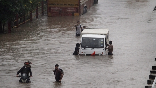 Commuters push their vehicle down the waterlogged Delhi-Gurugram Expressway service road after rainfall in Gurugram on Thursday,&nbsp;(PTI)