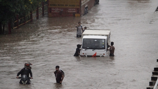 Commuters push their vehicle down the waterlogged Delhi-Gurugram Expressway service road after rainfall in Gurugram on Thursday,&nbsp;(PTI)