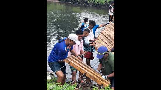 Thane professionals constructing bridge using rope and wood across river in Bitharwadi village in Shahapur. (HT PHOTO)