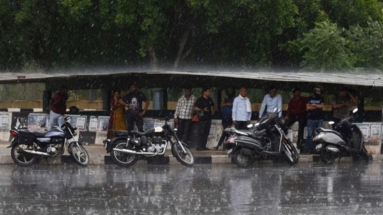 Commuters take shelter from the rain in Gurugram. (Vipin Kumar/HT Photo)