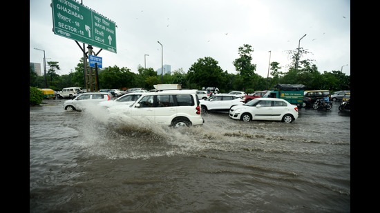 Commuters make their way through a heavily waterlogged stretch in Sector 95, Noida, on Thursday. (Sunil Ghosh/Hindustan Times)