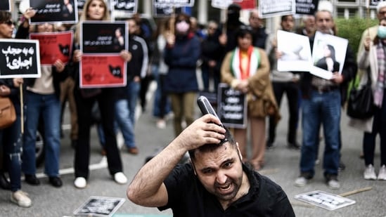 A man cuts his hair during a demonstration in support of Mahsa Amini in front of the Iranian embassy in Brussels on Saturday, following the death of an Iranian woman after her arrest by the country's morality police in Tehran.(AFP)