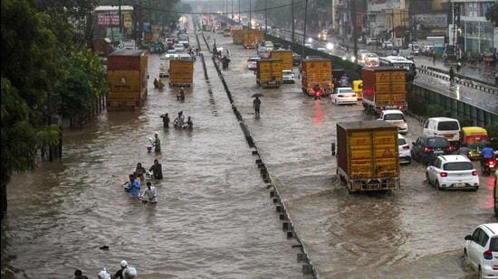 Commuters wade through waterlogged Delhi-Gurugram Expressway after rainfall on Thursday. (PTI)