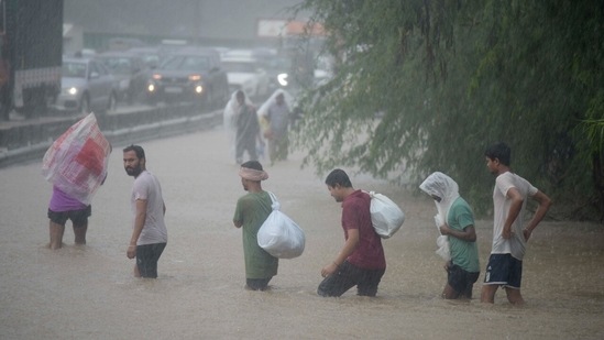 Pedestrains try to cross a water-logged road in Gurugram. (Photo by Parveen Kumar/Hindustan Times)
