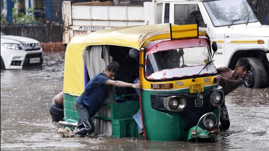 People push an auto through a waterlogged road amid heavy rainfall in New Delhi. (ANI) People push an auto through a waterlogged road amid heavy rainfall in New Delhi. (ANI)