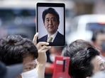 Shinzo Abe's State Funeral: A person holds a tablet computer displaying a photograph of former Japanese Prime Minister Shinzo Abe. Shinzo Abe's State Funeral: A person holds a tablet computer displaying a photograph of former Japanese Prime Minister Shinzo Abe.