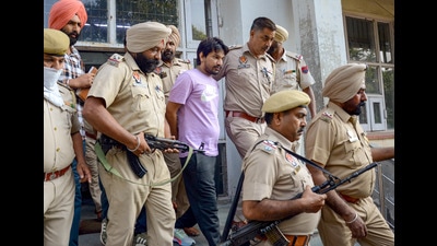 Punjab Police personnel produce Deepak Mundi, accused in the Sidhu Moose Wala and gangster Rana Kandowalia murder cases, in a court in Amritsar on Monday. (PTI)