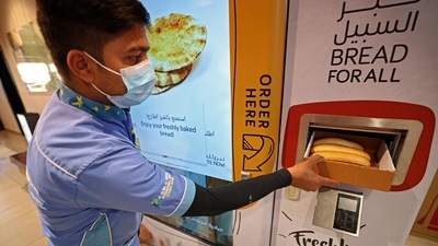 A man collects items from a vending machine that gives out free bread in Dubai. (AFP) A man collects items from a vending machine that gives out free bread in Dubai. (AFP)