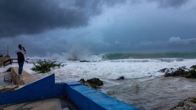 A woman takes photos while waves crash against a seawall as Hurricane Ian passes through George Town, Grand Cayman island. (AP) A woman takes photos while waves crash against a seawall as Hurricane Ian passes through George Town, Grand Cayman island. (AP)