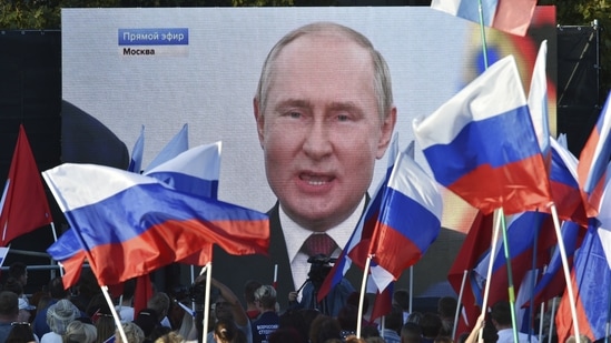 People watch on a large screen as Russian President Vladimir Putin delivers his speech after a ceremony to sign the treaties for four regions of Ukraine to join Russia in Kremlin.(AP)