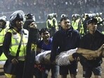 Football fans carry an injured man following clashes during a match at Kanjuruhan Stadium in Malang, East Java, Indonesia(AP)