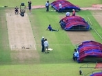 Groundsmen dry the playing field after rains at Vidarbha Cricket Association Stadium