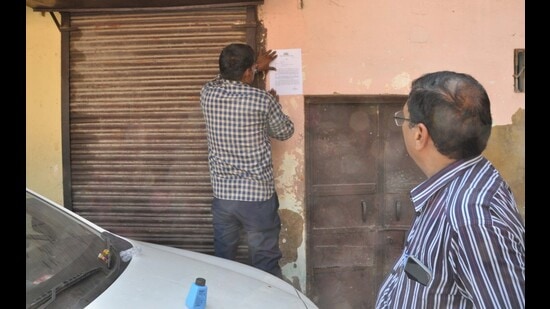 An ADA staff pasting a notice for closing business activities on a closed shop in Tajganj locality of Agra. (HT photo)