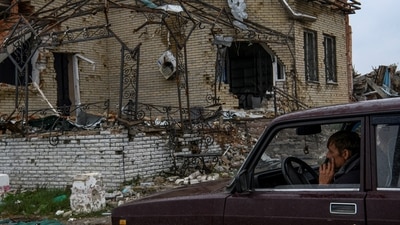 Russia-Ukraine War: A local resident sits inside a car next to a destroyed house, amid Russia's attack on Ukraine, in the village of Dolyna, Donetsk region. (Reuters)
