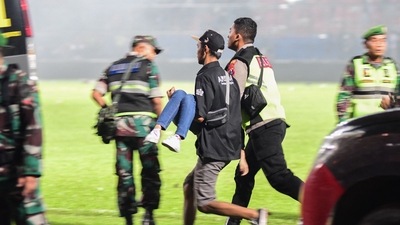 This picture taken on October 1, 2022 shows people running with an injured spectator after a football match between Arema FC and Persebaya at the Kanjuruhan stadium in Malang, East Java. (AFP) This picture taken on October 1, 2022 shows people running with an injured spectator after a football match between Arema FC and Persebaya at the Kanjuruhan stadium in Malang, East Java. (AFP)