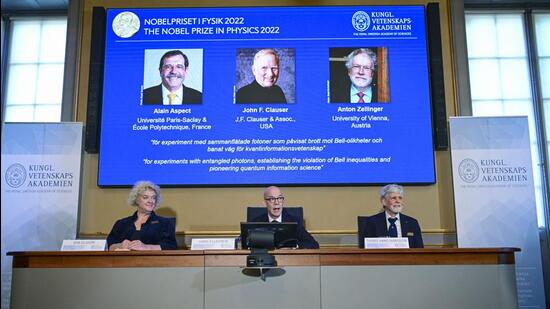 Secretary General of the Royal Swedish Academy of Sciences Hans Ellegren, centre, Eva Olsson, left and Thors Hans Hansson, members of the Nobel Committee for Physics announce the winner of the 2022 Nobel Prize in Physics, from left to right on the screen, Alain Aspect, John F. Clauser and Anton Zeilinger in Stockholm on Tuesday. (AP)