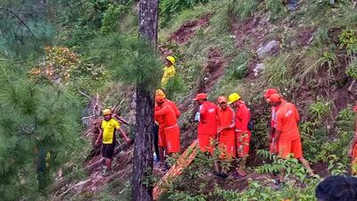 NDRF personnel shift the body of a victim during a search and rescue operation after a bus carrying members of a marriage party fell into a gorge, in Pauri Garhwal district, Wednesday. (PTI)