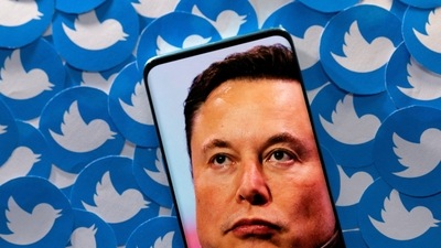Elon Musk Twitter Deal: An image of Elon Musk is seen on a smartphone placed on printed Twitter logos. (Reuters)