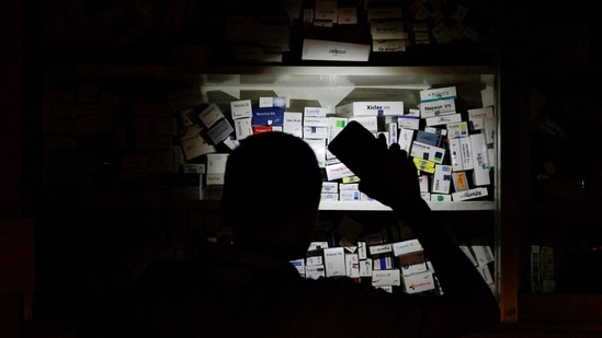 Bangladesh Blackout: A salesman of a pharmaceutical shop uses his cellphone torch to find medicine in Dhaka, Bangladesh.(Reuters)