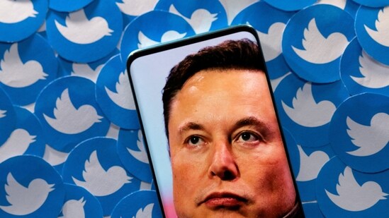 Elon Musk Twitter Deal: An image of Elon Musk is seen on a smartphone placed on printed Twitter logos.(Reuters)
