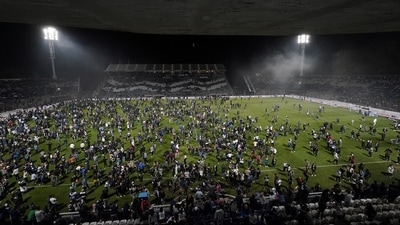 Fans of Gimnasia y Esgrima La Plata affected by tear gas invade the field after the match between Gimnasia y Esgrima La Plata and Boca Juniors in the Liga Profesional 2022. (Reuters)