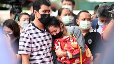 A husband comforts his wife as she holds their child's milk bottle and blanket while standing outside the nursery where the mass shooting took place. (AFP) A husband comforts his wife as she holds their child's milk bottle and blanket while standing outside the nursery where the mass shooting took place. (AFP)