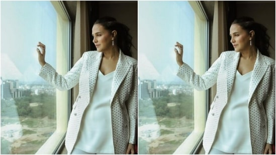 Neha decked up in a white satin top and a pair of white formal trousers. She added the necessary bling to her look with a white jacket, sequined in silver mirror work.(Instagram/@nehadhupia)