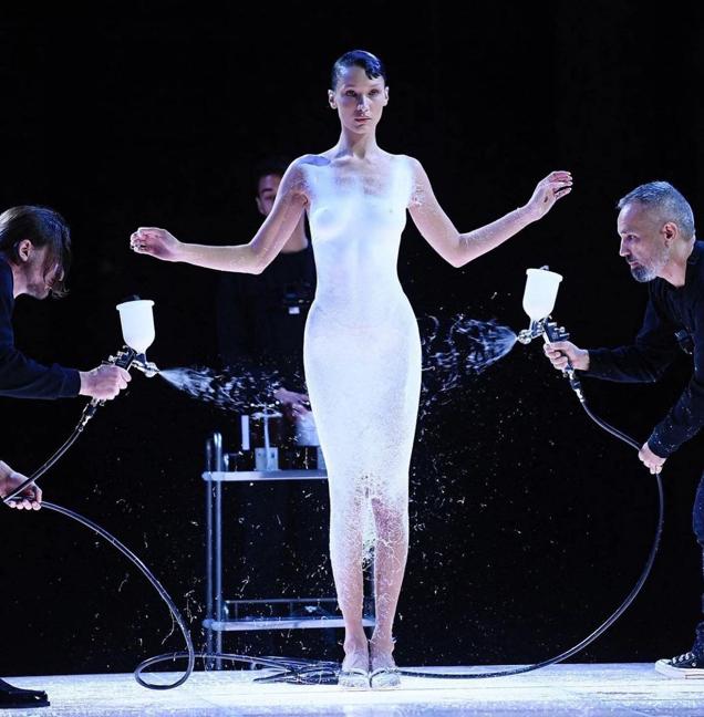 Scientific experts spray paint the minimalist slip dress directly on Bella Hadid’s body (Photo: Instagram) Scientific experts spray paint the minimalist slip dress directly on Bella Hadid’s body (Photo: Instagram)