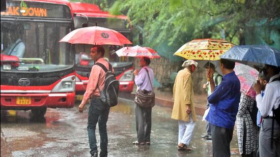 Commuters out in the rain at the DTC Mehrauli Bus Terminal in New Delhi, India, on Saturday, October 8, 2022. (Photo by Raj K Raj/ Hindustan Times)