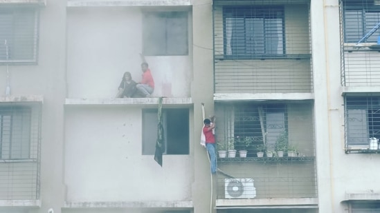 Residents can be seen hanging from windows as a fire breaks out at a residential building in Mumbai's Chembur. (HT Photo)