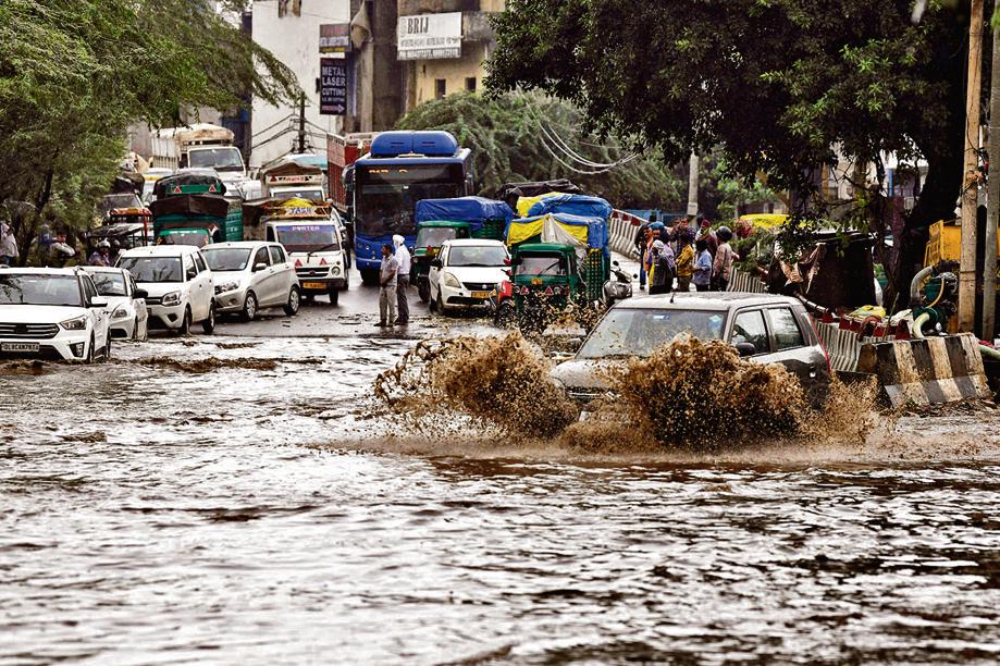 Vehicles wade through a waterlogged road following heavy rainfall, in New Delhi on Saturday. (ANI Photo)