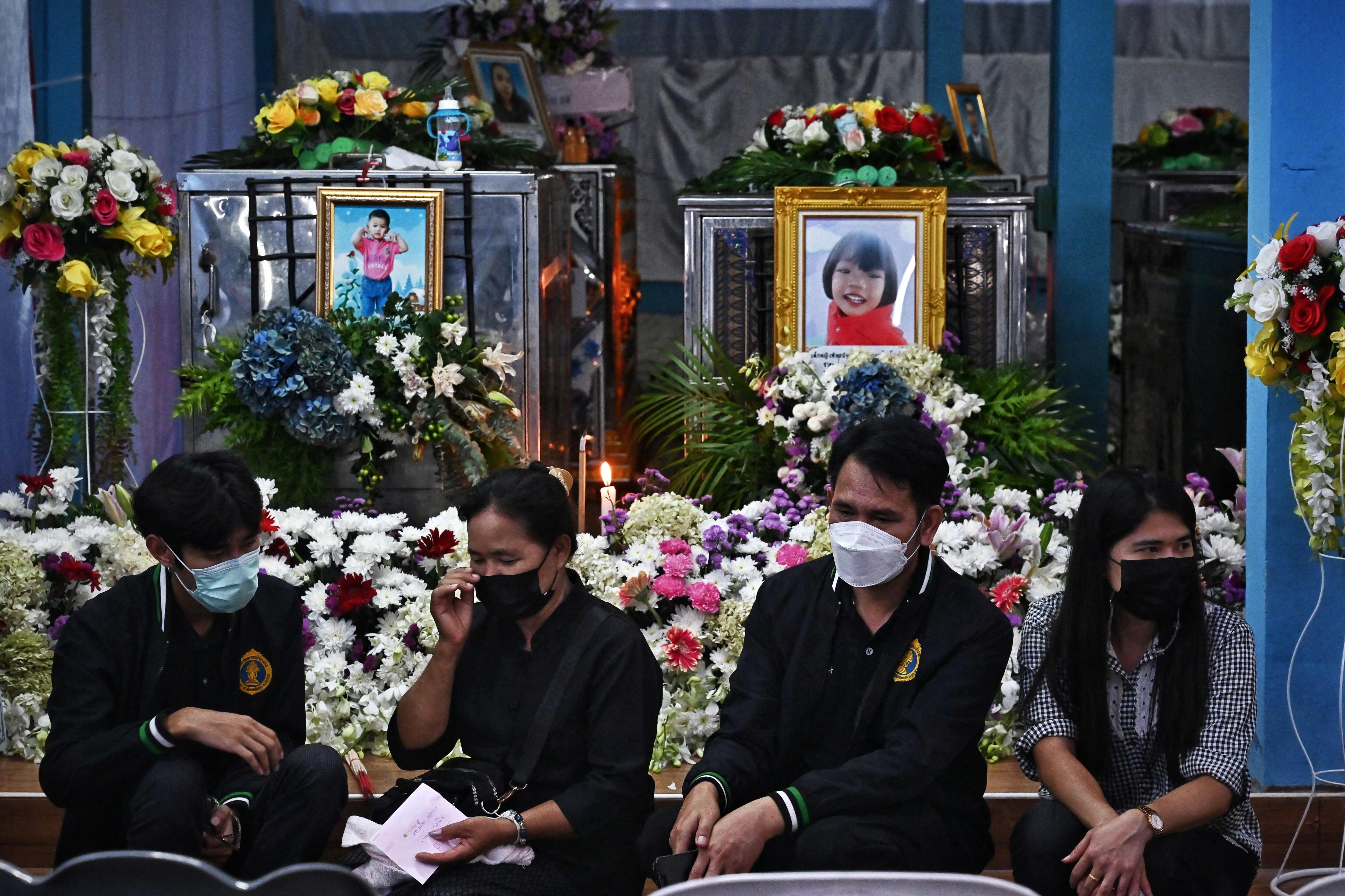 Relatives sit in front of the coffins of victims of the nursery mass shooting at Wat Si Uthai temple in Thailand's northeastern Nong Bua Lam Phu province on October 8, 2022. (Photo by Lillian SUWANRUMPHA/AFP) Relatives sit in front of the coffins of victims of the nursery mass shooting at Wat Si Uthai temple in Thailand's northeastern Nong Bua Lam Phu province on October 8, 2022. (Photo by Lillian SUWANRUMPHA/AFP)