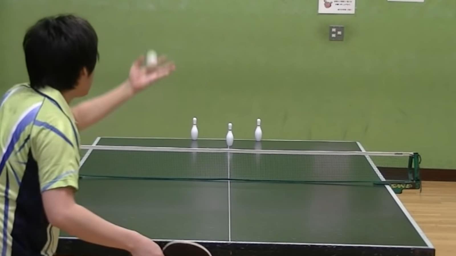 Table tennis player strikes bowling pins with ping-pong balls