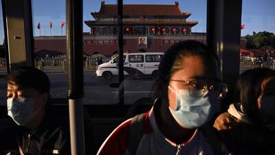 Passengers on a bus look on as they drive past the Tiananmen Gate in Beijing on Sunday. (AFP) Passengers on a bus look on as they drive past the Tiananmen Gate in Beijing on Sunday. (AFP)