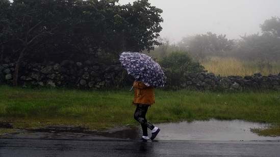 A woman walks under heavy rain along the road in the municipality of Santa Ana, department of Francisco Morazan, Honduras, before the arrival of Hurricane Julia.&nbsp;(AFP)