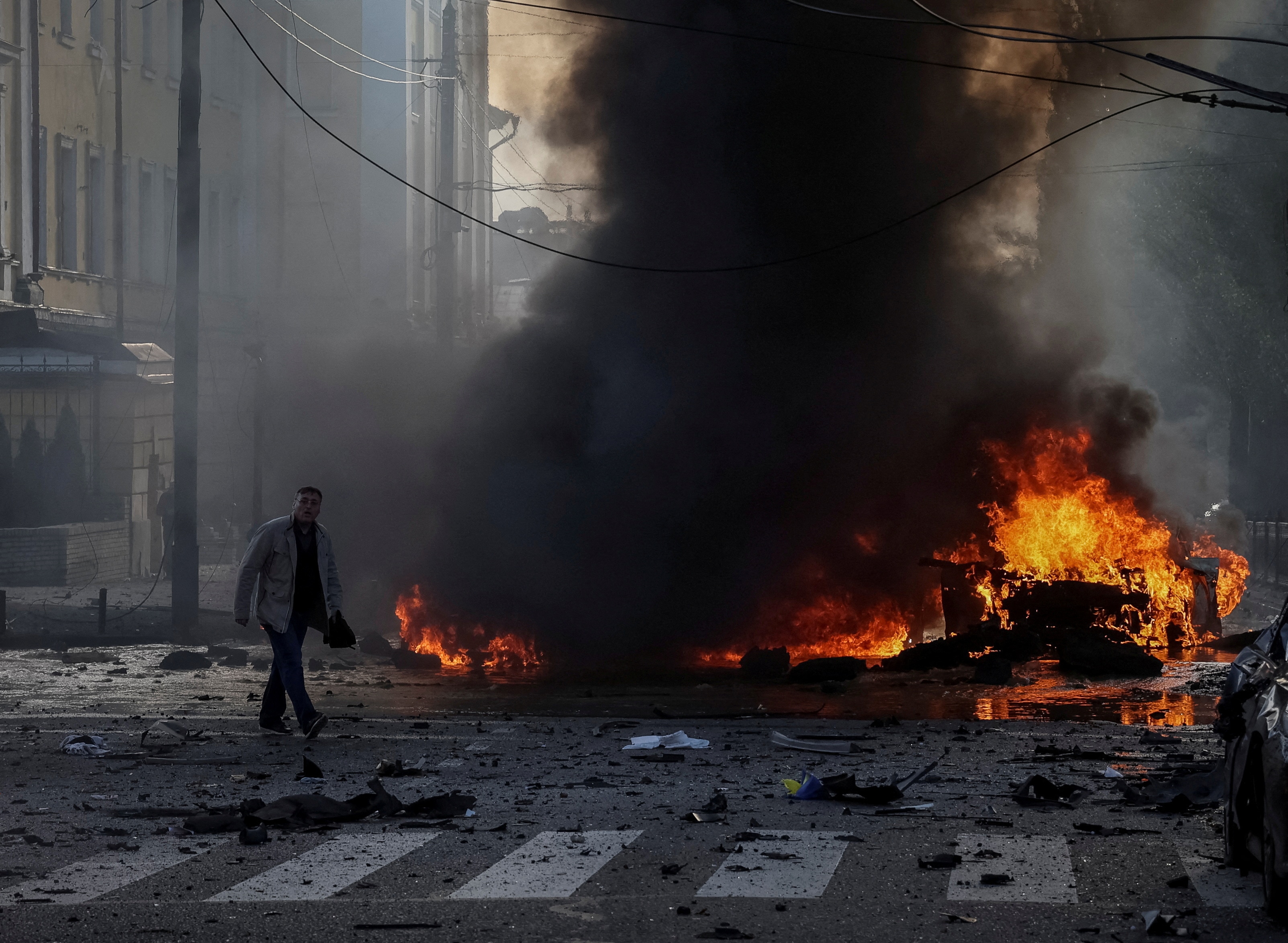 A driver walks near his burned car after Russian military strike, as Russia's invasion of Ukraine continues, in central Kyiv, Ukraine. (REUTERS)
