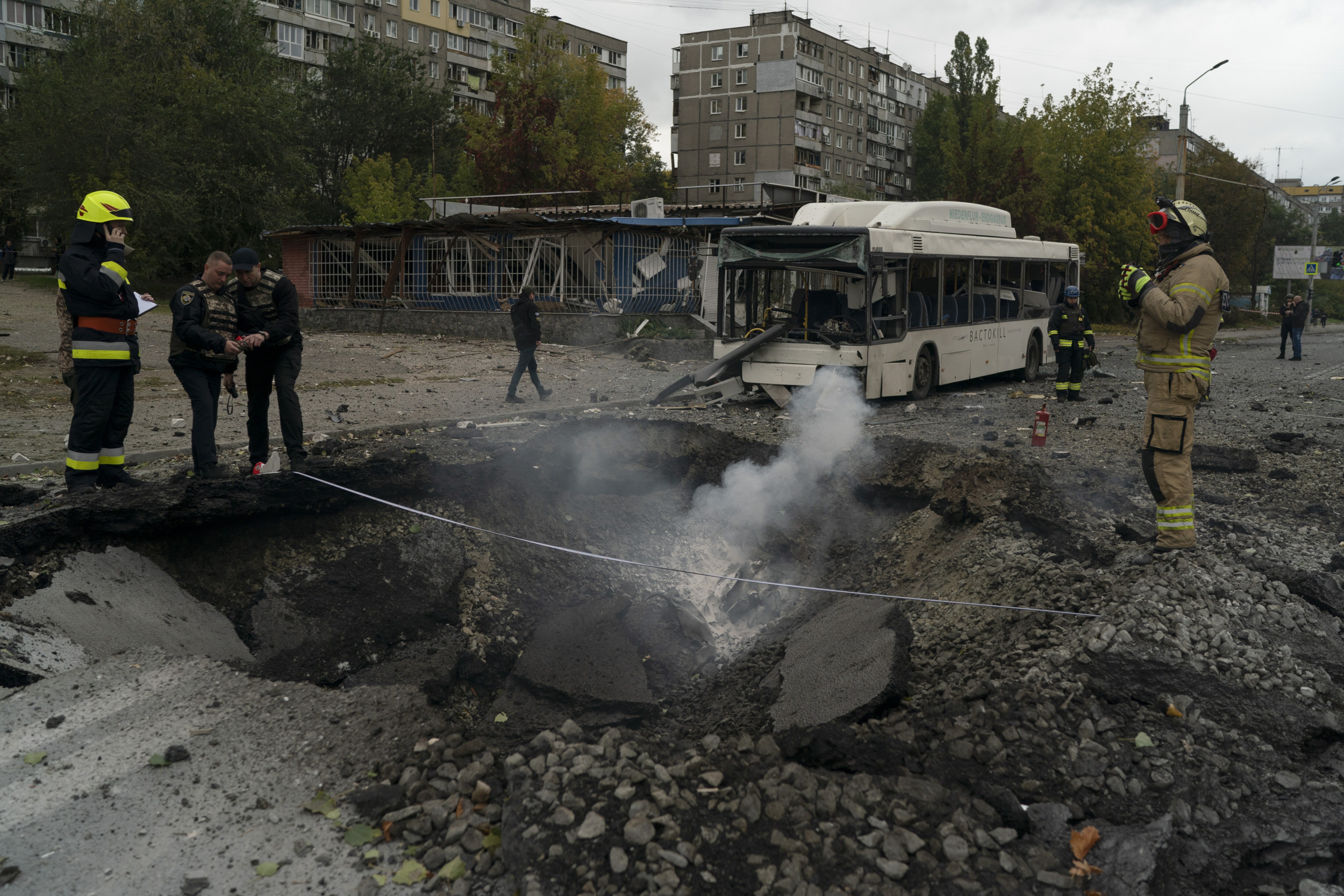 Firefighters and police officers work on a site where an explosion created a crater on the street after a Russian attack in Dnipro, Ukraine, Monday, October 10, 2022.(AP Photo/Leo Correa)