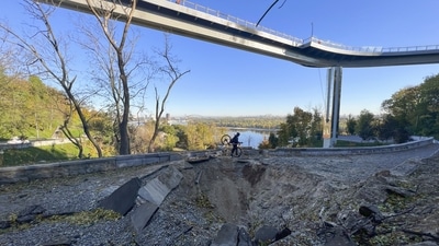 Russia-Ukraine War: A man carries his bike past a rocket crater under a pedestrian bridge, after Monday rocket attack in center Kyiv, Ukraine. (AP)