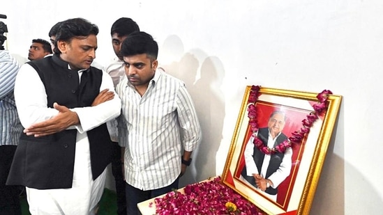 Samajwadi Party (SP) leader Akhilesh Yadav stands next to a portrait of his father Mulayam Singh Yadav in Saifai on Monday.(ANI/ Samajwadi Party Twitter)