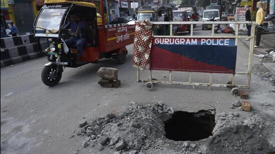 A portion of the Basai Road near Khandsa Chowk caved in on Tuesday morning, leaving a gaping hole in the carriageway towards Jhajjar and Pataudi. (HiVipin Kumar/HT Photo)