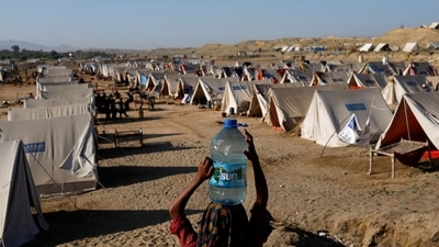 Pakistan Floods: A displaced girl carries a bottle of water she filled from nearby stranded flood-waters in Sehwan, Pakistan. (Reuters)