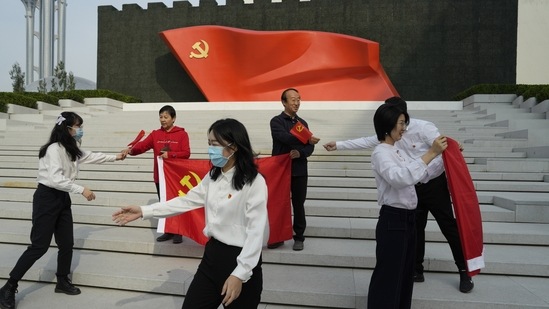 Visitors to the Museum of the Communist Party of China holds party flags to pose for photos in Beijing.(AP)