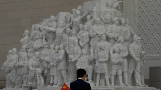 A visitor to the Museum of the Communist Party of China holds a party flag near a sculpture depicting heroic workers in Beijing, Wednesday.(AP)
