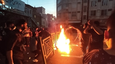Protesters make fire and block the street during a protest over the death of a woman who was detained by the morality police, in downtown Tehran, Iran. (AP)