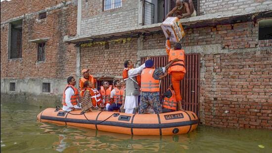 Prayagraj: Deputy Chief Minister of Uttar Pradesh Keshav Prasad Maurya distributes food packets and flood relief material to flood affected people in a residential colony as the water level of the Ganga and Yamuna rivers continues to stay high in the ongoing monsoon season, in Prayagraj, Tuesday, August 30, 2022. (PTI Photo) (PTI08_30_2022_000205A) (PTI)