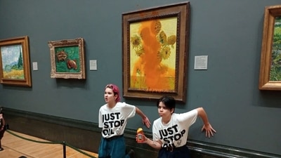 Activists of "Just Stop Oil" glue their hands to the wall after throwing soup at Van Gogh's ‘Sunflowers’ at the National Gallery in London,&nbsp; (via REUTERS)